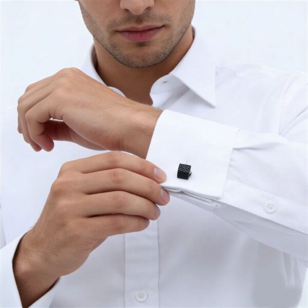 Homme ajustant des boutons de manchette noirs carrés sur une chemise blanche
